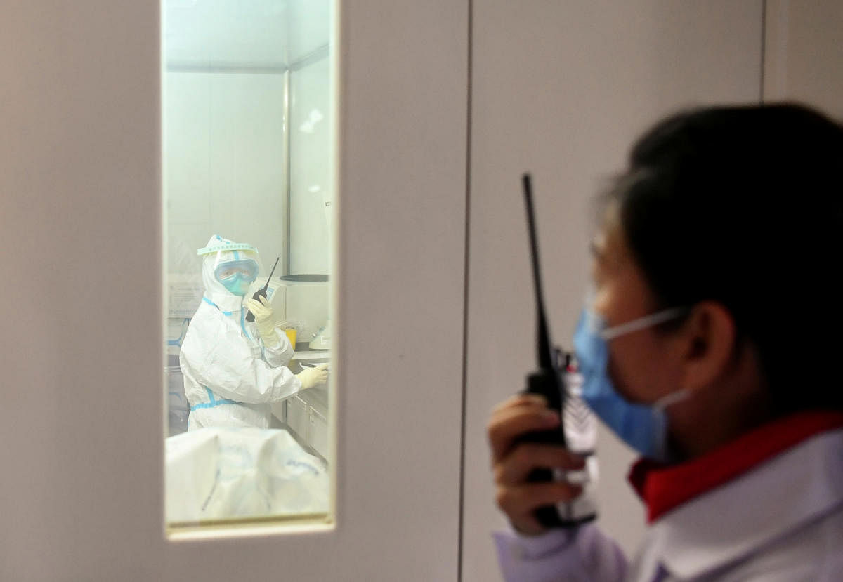 A member of a coronavirus prevention and control team communicates through walkie-talkie with a colleague inside a laboratory at the Ningxia Center for Diseases Prevention and Control in Yinchuan, Ningxia Hui Autonomous Region, China February 2, 2020. Picture taken February 2, 2020. (Credit: REUTERS Photo)