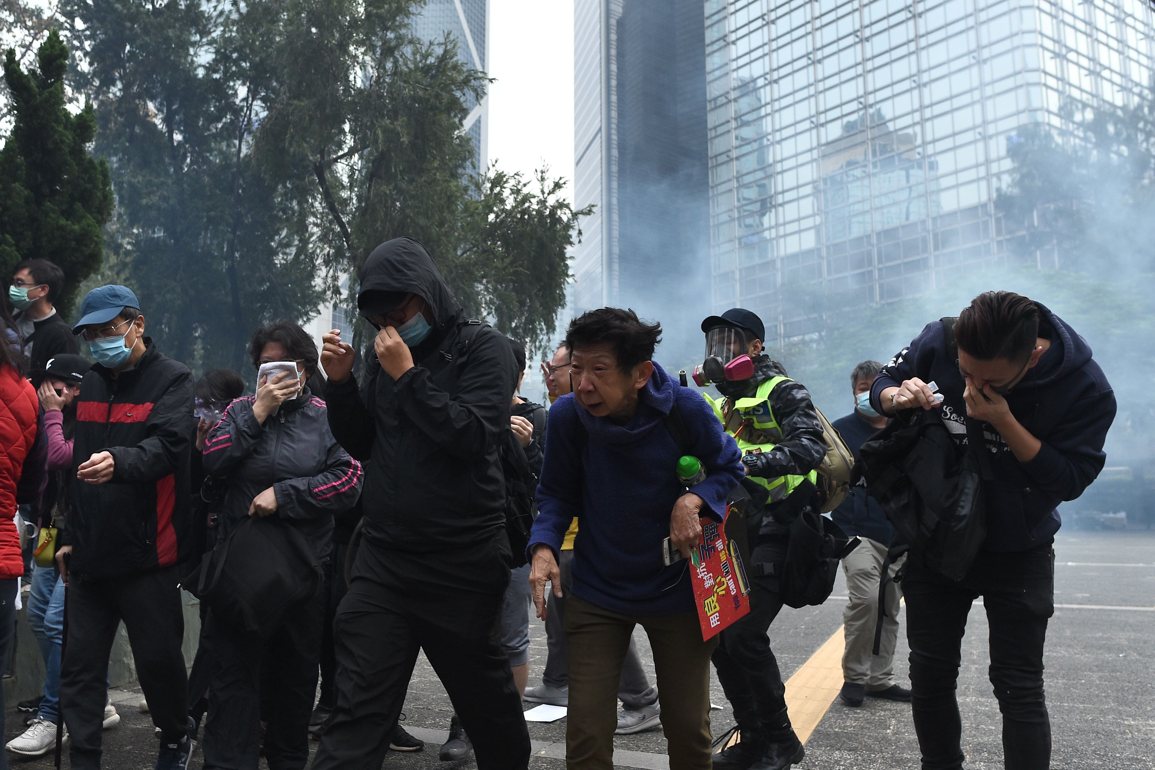 People react from tear gas fired by police to disperse the crowd gathered for the 'universal siege on communists' rally at Chater Garden in Hong Kong. (AFP Photo)