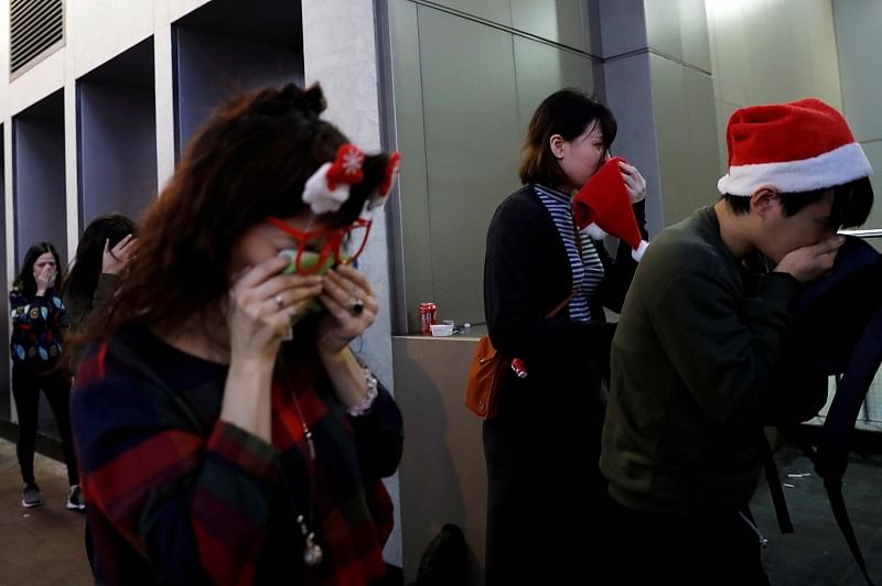 People wearing Santa hats react from tear gas during an anti-government protest on Christmas Eve in Hong Kong. (Reuters Photo)