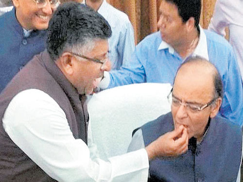 I&B Minister Ravi Shankar Prasad offers sweets to Finance Minister Arun Jaitley after the GST Bill was passed by the Rajya Sabha in New Delhi on Wednesday evening. PTI