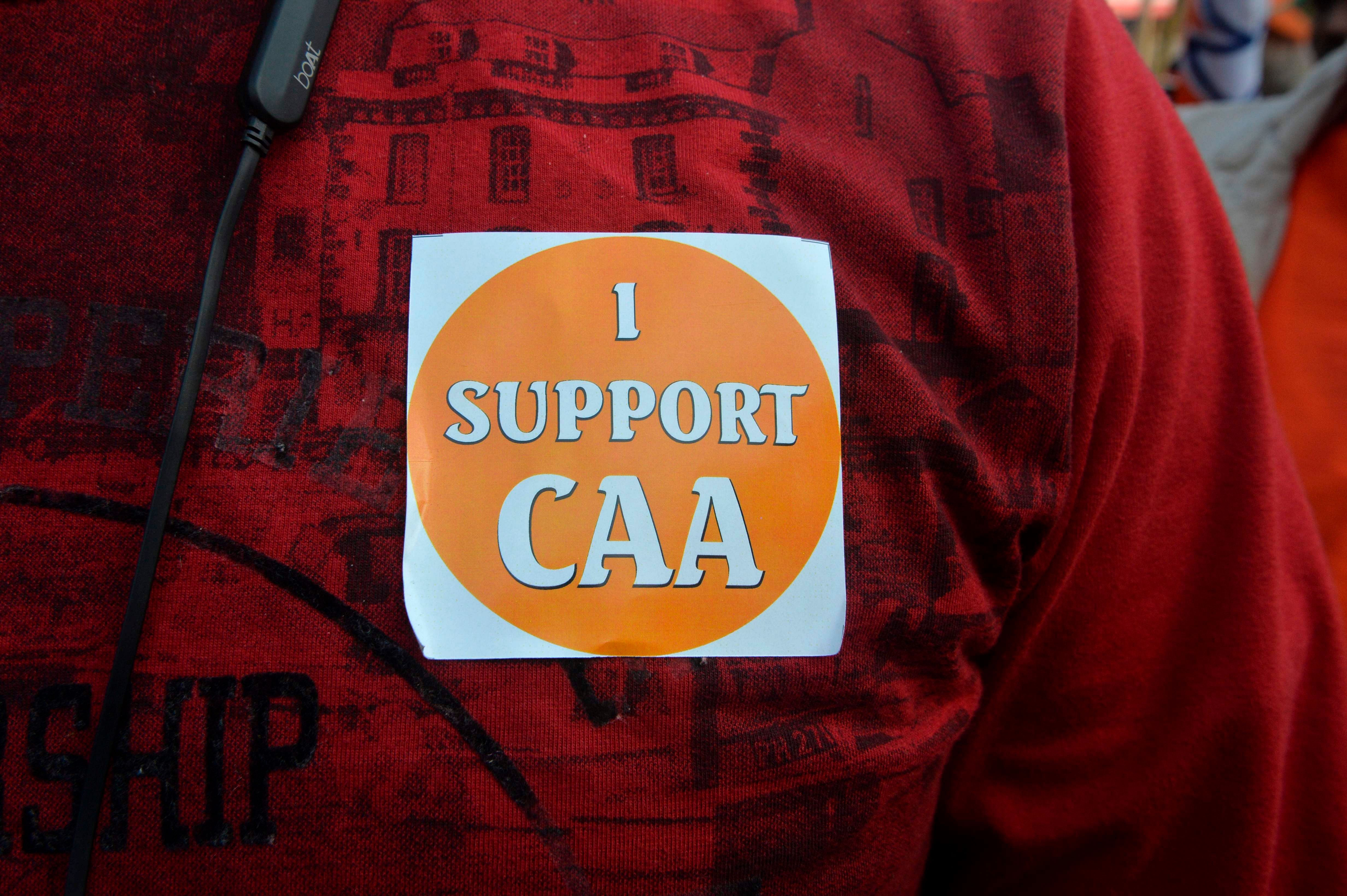A supporter of the Bharatiya Janata Party (BJP) displays a sticker reading "I Support CAA" during a rally in support of India's new citizenship law in Siliguri. (PTI Photo)