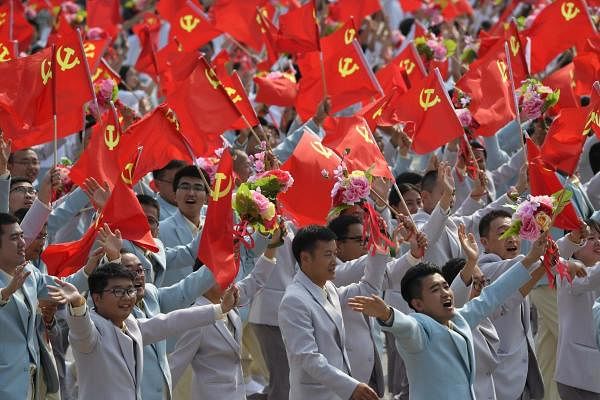 People wave Communist Party flags during a military parade in Tiananmen Square in Beijing. (Photo/AFP)