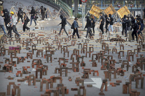 Protesters walk past barricades of bricks on a road near the Hong Kong Polytechnic University in Hong Kong. (AP photo)