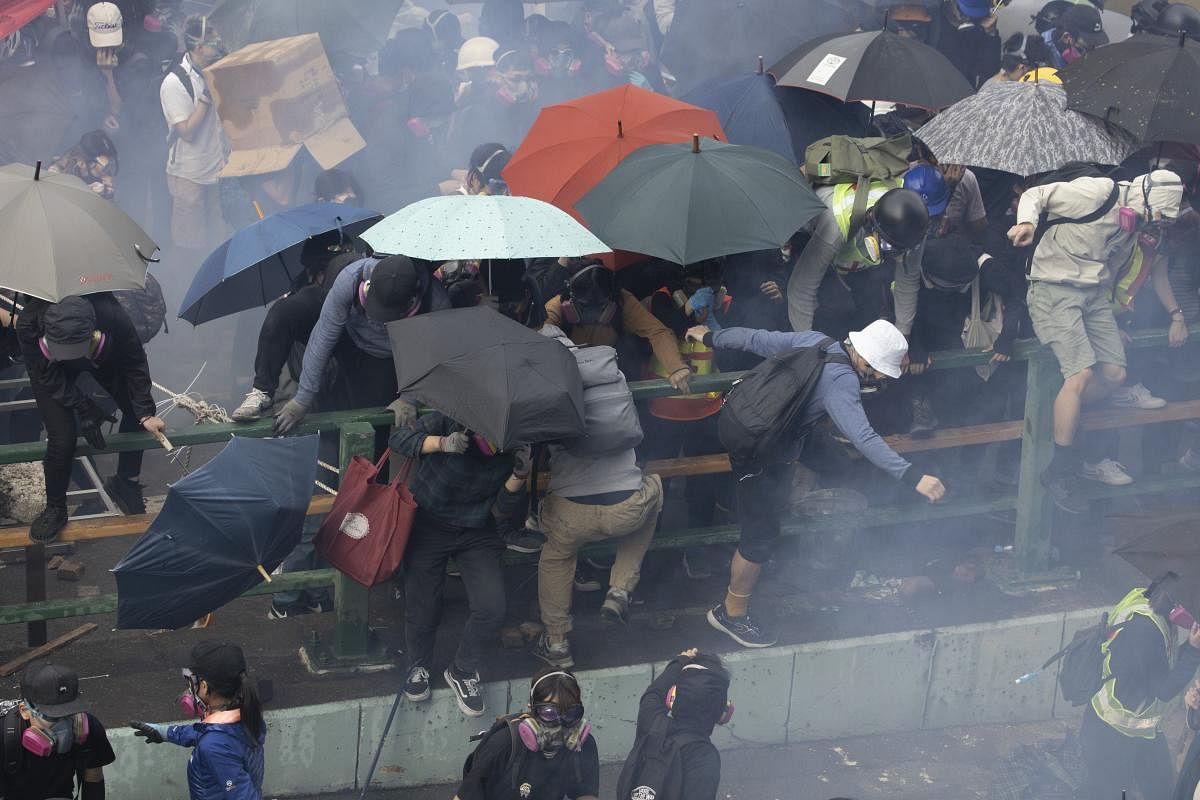 Protesters scramble over a railing at the Hong Kong Polytechnic University as tear gas fired by the police fills the air in Hong Kong on Monday, Nov. 18, 2019. (AP/PTI)