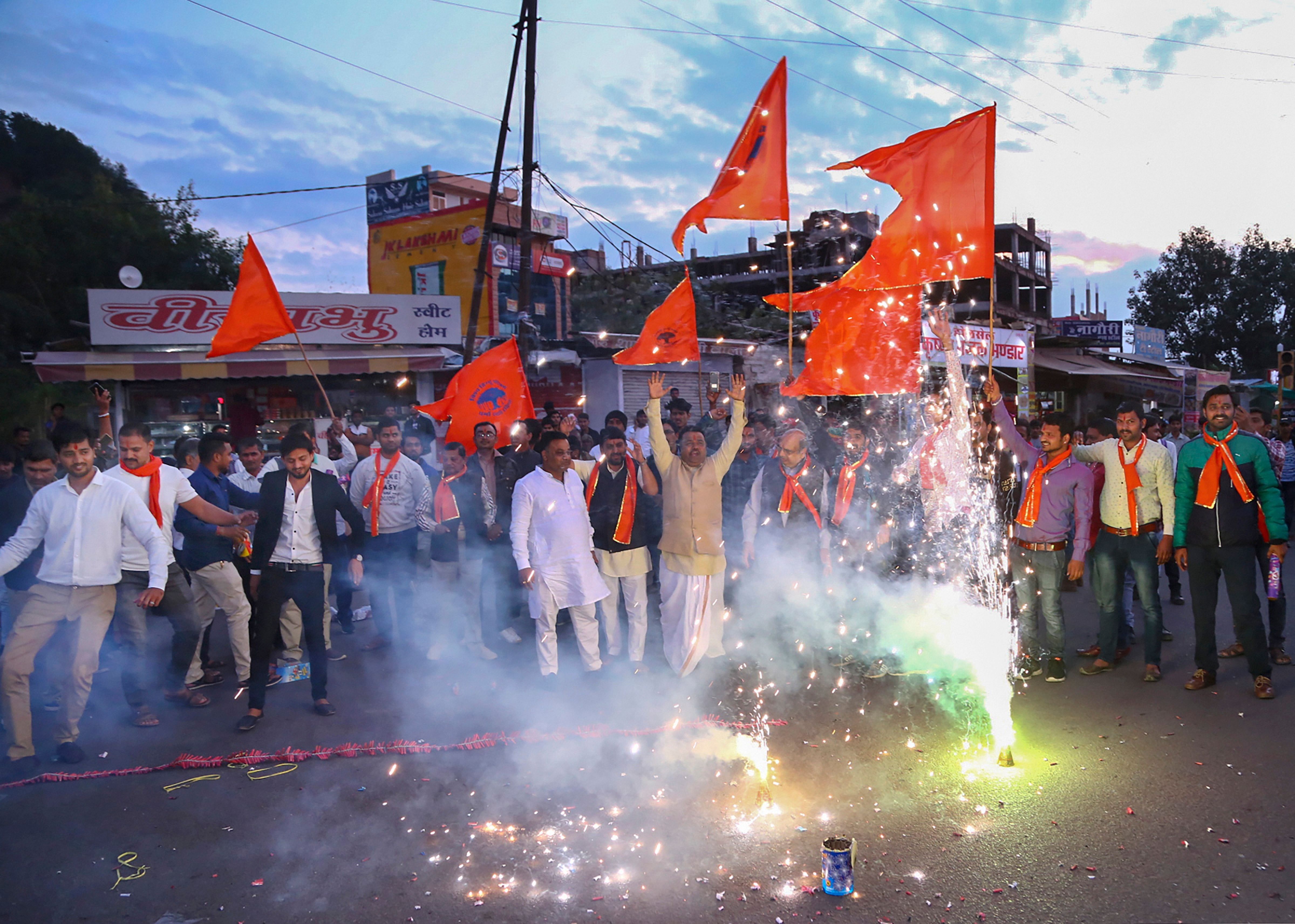 Hindu refugees from Pakistan burst firecrackers with member of Vishwa Hindu Parishad (VHP) as they celebrate the approval of the government's Citizenship Amendment Bill. (PTI Photo)