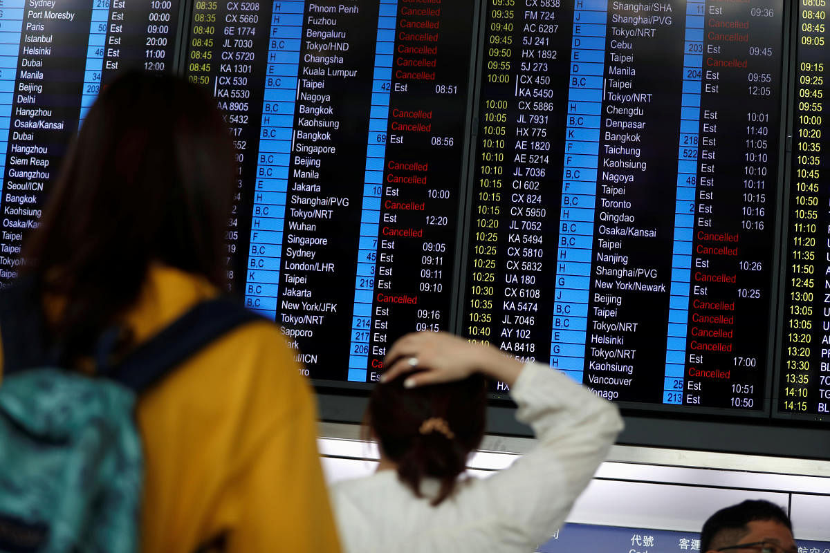 Passengers react as they look at the flight information board as the airport reopened a day after flights were halted due to a protest, at Hong Kong International Airport on August 13, 2019. (REUTERS)