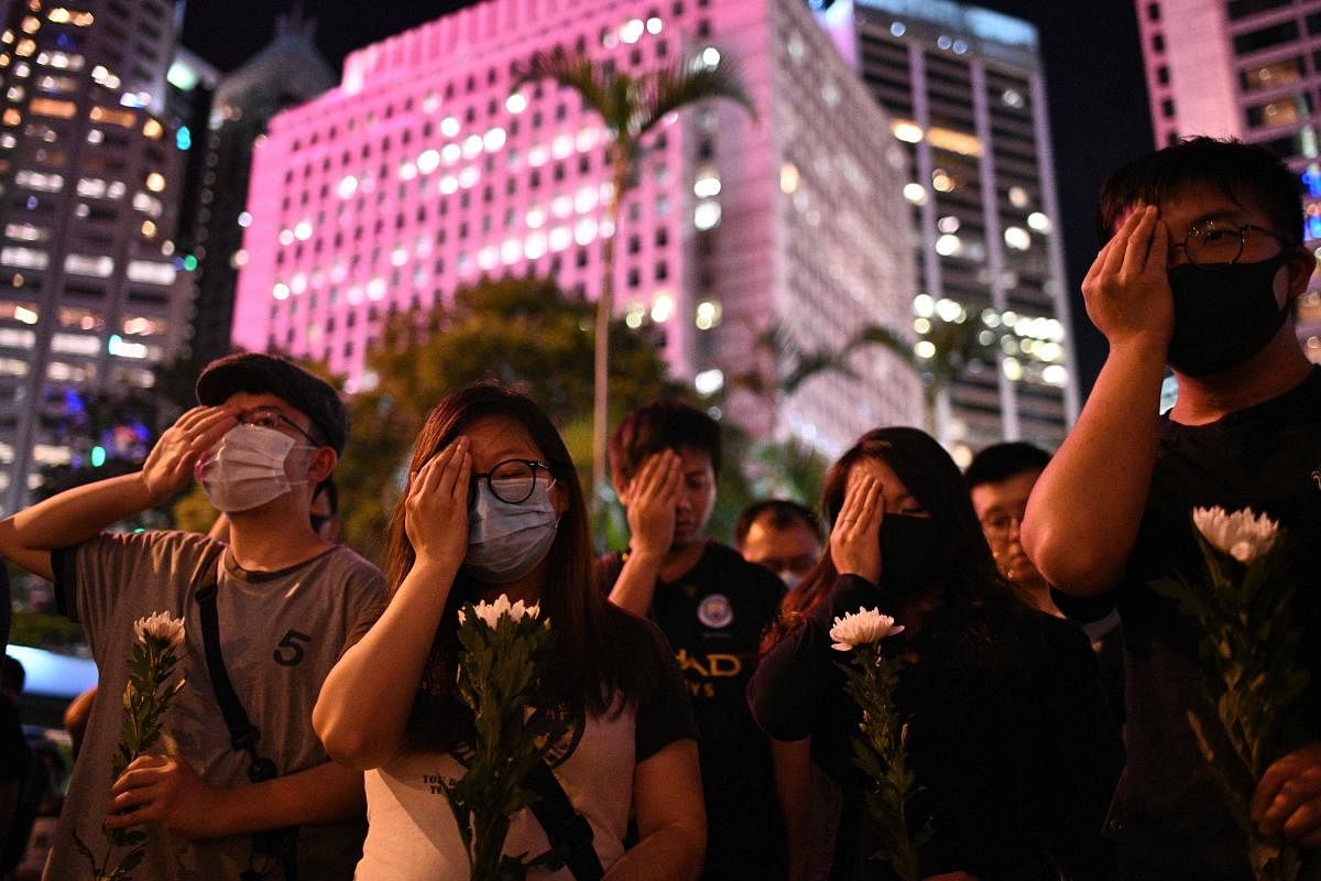 Protesters cover their right eyes as they attend the Stand in Silence for the 74th Anniversary of the Liberation of Hong Kong gathering at the Cenotaph in Hong Kong (AFP Photo)