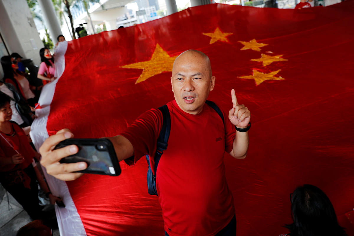 Pro-China supporter Alex Yeung, owner of Wah Kee Restaurant, reacts next to a giant Chinese national flag as he and others celebrate China's National Day in Hong Kong, China October 1, 2019. Reuters