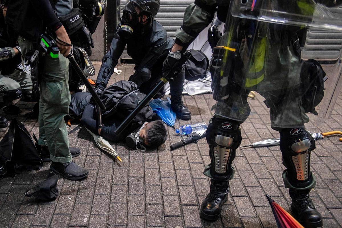 TOPSHOT - A protester (C) is detained by police during clashes with protesters at the Wan Chai district in Hong Kong on October 6, 2019. - Hong Kong was rocked by fresh violence on October 6 as tens of thousands hit the streets to defy a ban on face masks