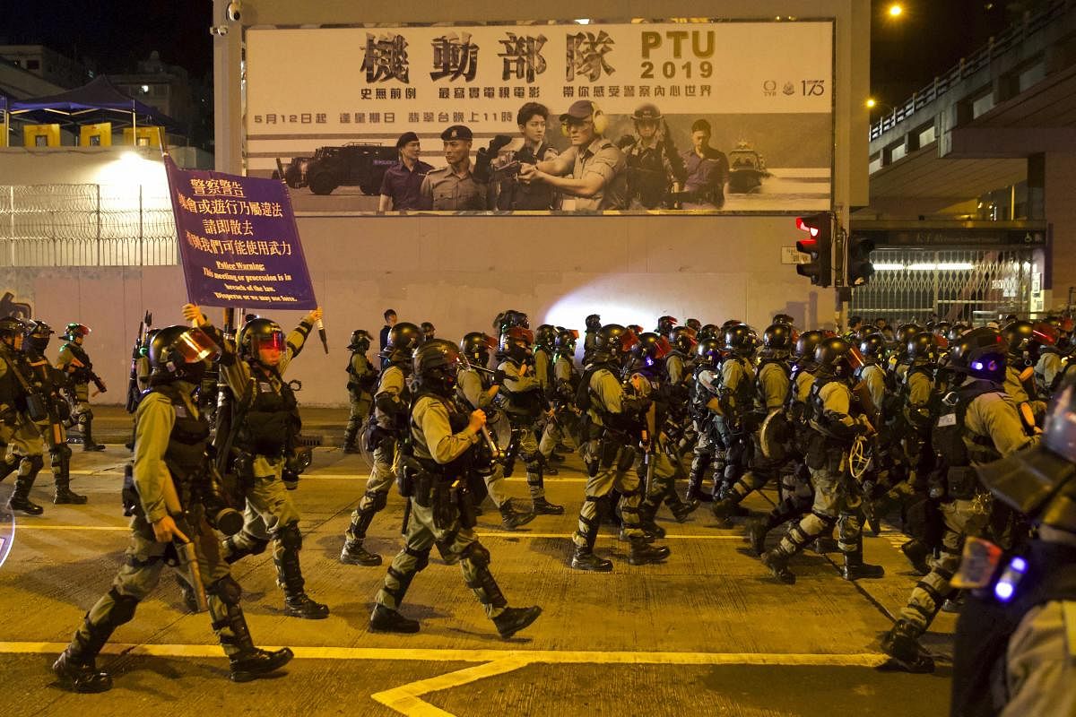 Riot policemen hold aloft a warning banner as they advance along a road in Hong Kong, Saturday, Nov. 30, 2019. (PTI Photo)