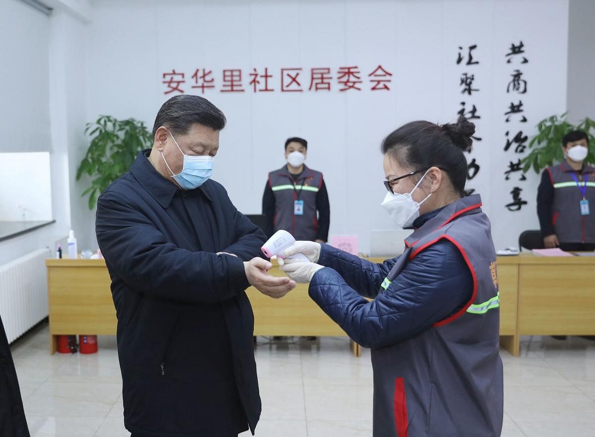This photo released on February 10, 2020 by China's Xinhua News Agency shows Chinese President Xi Jinping (L) wearing a protective facemask as a health official (R) checks his body temperature during an inspection of the novel coronavirus pneumonia prevention and control work at the Anhuali Community in Beijing. hoto by JU PENG / XINHUA / AFP