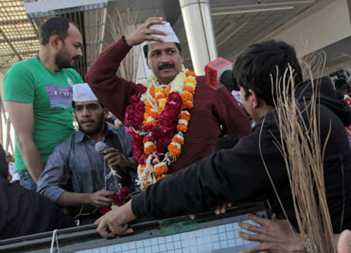 Anti-graft activist and leader of Aam Aadmi Party, or Common Man Party, Arvind Kejriwal holds on to his cap as he rides an open jeep upon his arrival for a four-day visit of Gujarat state ahead of the elections, in Ahmadabad, Wednesday, March 5, 2014.  AP Photo