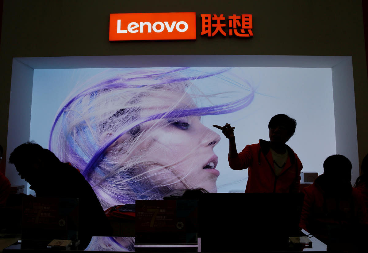 FILE PHOTO: An employee gestures next to a Lenovo logo at Lenovo Tech World in Beijing, China November 15, 2019. REUTERS/Jason Lee/File Photo
