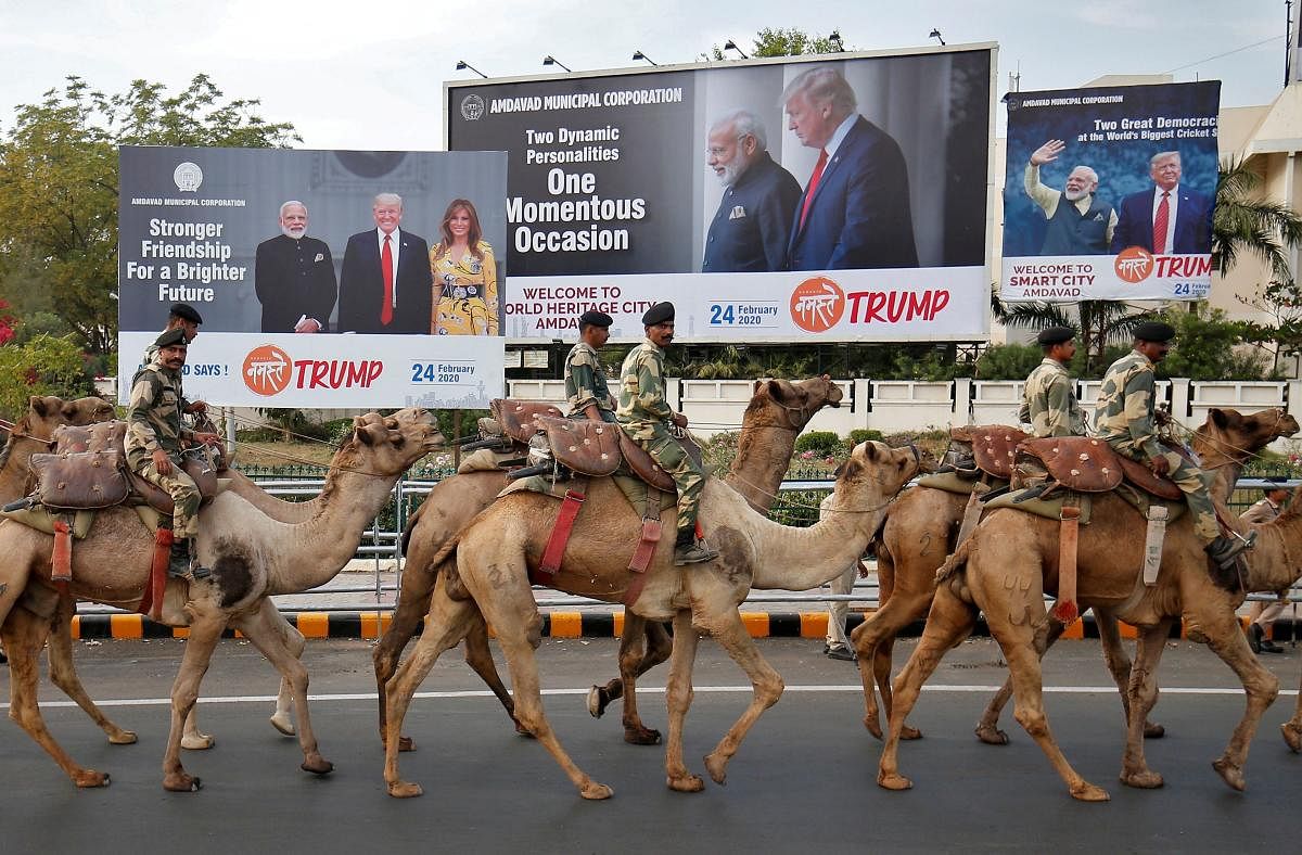 BSF soldiers ride their camels past hoardings with the images of India's Prime Minister Narendra Modi, U.S. President Donald Trump and first lady Melania Trump, as they take part in a rehearsal for a road show ahead of Trump's visit, in Ahmedabad. Credit: Reuters Photo