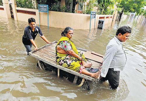 knee-deep : A woman is transported on a handcart along a flooded road after rain in Ahmedabad on Wednesday. REUTERS