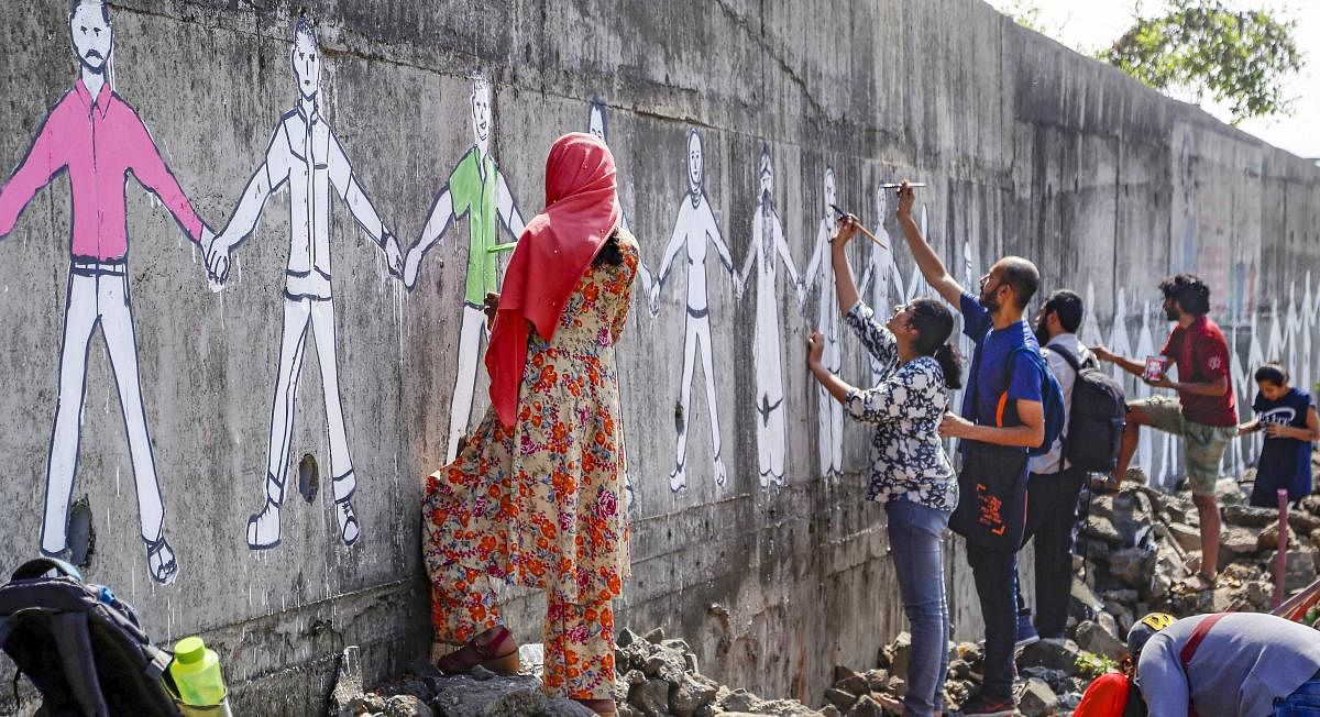  Artists paint a human chain on a wall during a protest against the Citizenship Amendment Act (CAA), at Mumbra in Mumbai. PTI