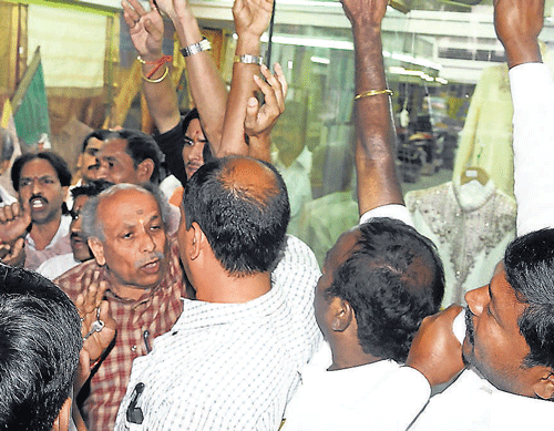 Recovery drive: Members of the BBMP Taxation and Finance committee pull down the shutter of a shop on KG Road on Tuesday. dh photo