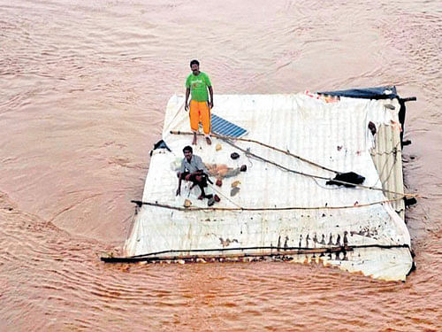 People on top of a submerged house wait to be rescued in flood-hit Valsad town in Gujarat on Tuesday after heavy rain. PTI