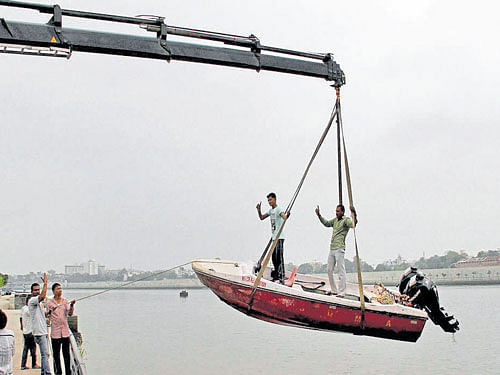 In action: Rescue guard team of Ahmedabad Fire and Emergency Service lifts a tourist boat from Sabarmati River in  Ahmedabad on Monday after the flood alert due to the release of water from Dharoi Dam. PTI