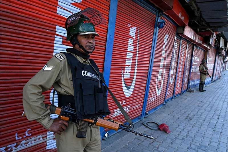 Security personnel stand guard in front of closed shops in Srinagar. (AFP Photo)
