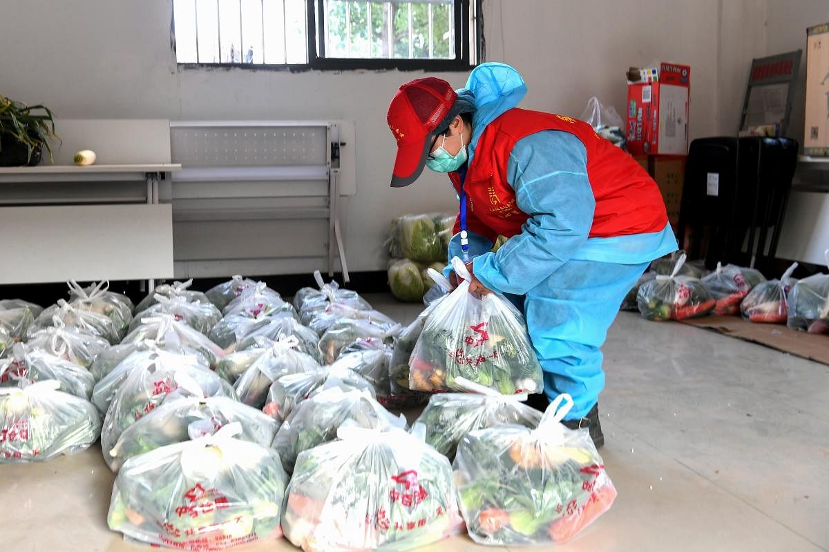 This photo taken on February 18, 2020 shows a community staff member carrying foods and daily necessities as she prepares to deliver for residents in Wuhan in China's central Hubei province. AFP