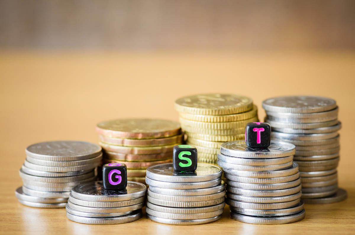 GST Concept with alphabet block on a gold stacked of coins.