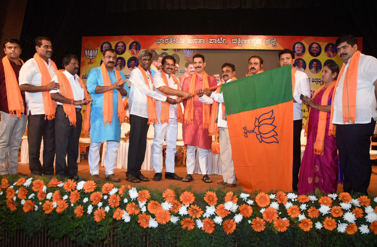 BJP state president and Dakshina Kannada MP Nalin Kumar Kateel hands over BJP flag to the newly elected BJP Dakshina Kannada president Sudarshan Moodbidri, during installation of office-bearers of the BJP district unit in Mangaluru on Monday. DH Photo