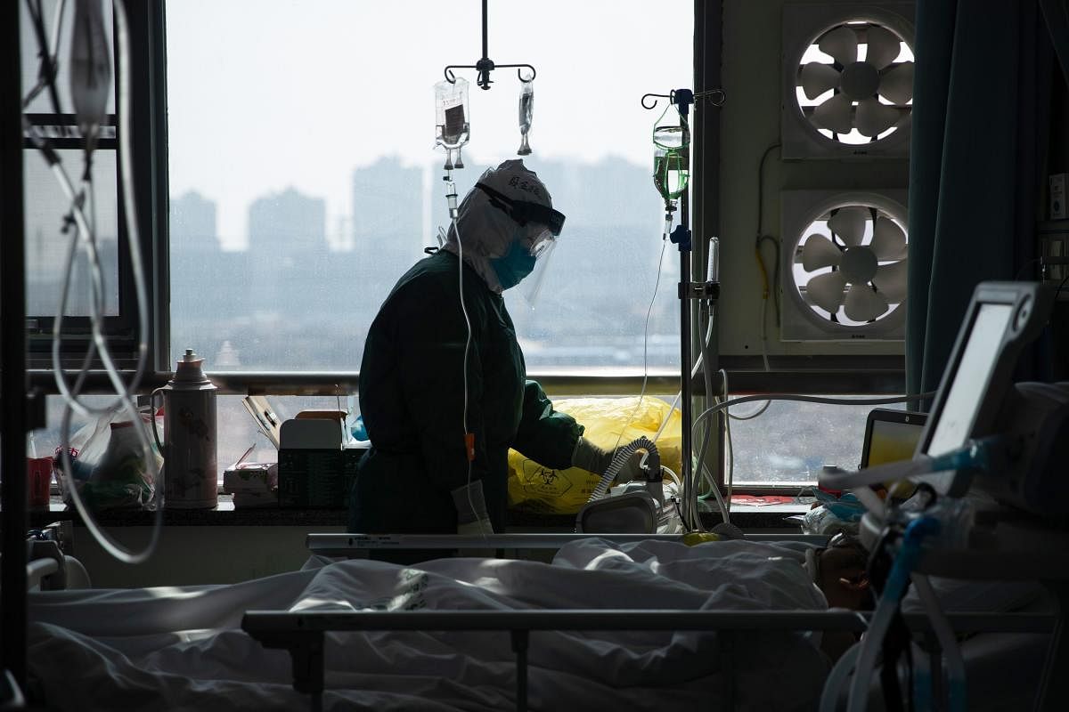 This photo taken on February 22, 2020 shows a medical staff member treating a patient infected by the COVID-19 coronavirus at a hospital in Wuhan in China's central Hubei province. AFP