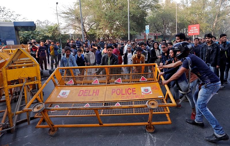 Demonstrators remove a police barricade during a protest against a new citizenship law outside the Jamia Millia Islamia university in New Delhi. (Reuters Photo)