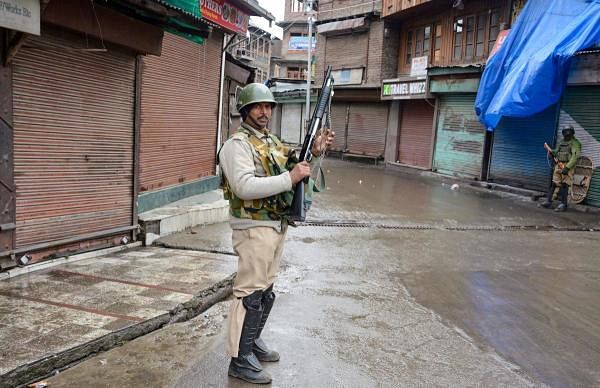 A security jawan stands guard in a deserted street of Srinagar. (PTI photo)