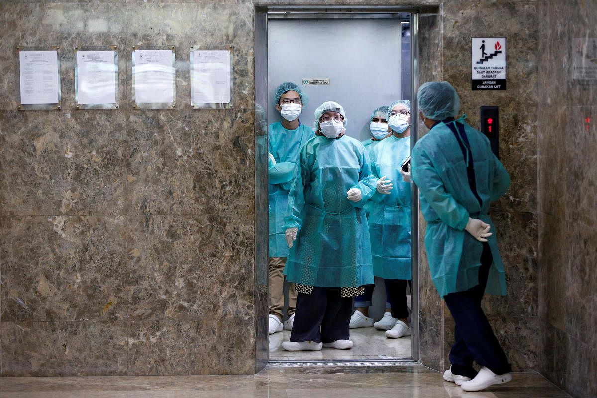 Journalists wear protective suits inside an elevator as they prepare for a media visit to Indonesian Health Ministry's Laboratorium for Research on Infectious-Diseases, following the outbreak of the new coronavirus in China, in Jakarta, Indonesia, Februar