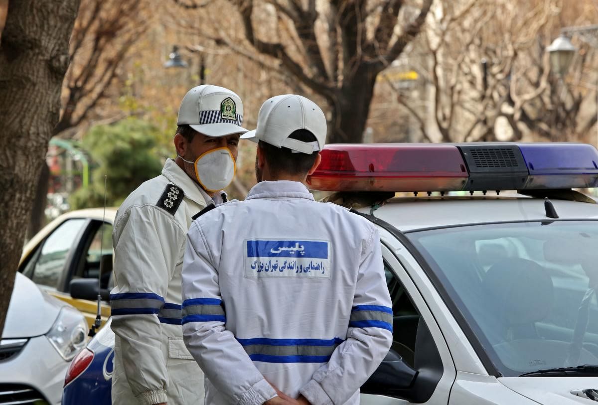 Emergency first responders wearing protective masks stand along a street in the Iranian capital Tehran on February 24, 2020. (AFP Photo)
