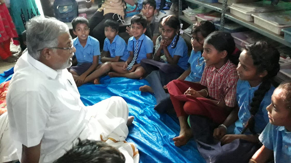 Minister for Primary and Secondary Education S Suresh Kumar interacts with children inside the makeshift building at Balooru Horatti in Mudigere taluk. dh photo
