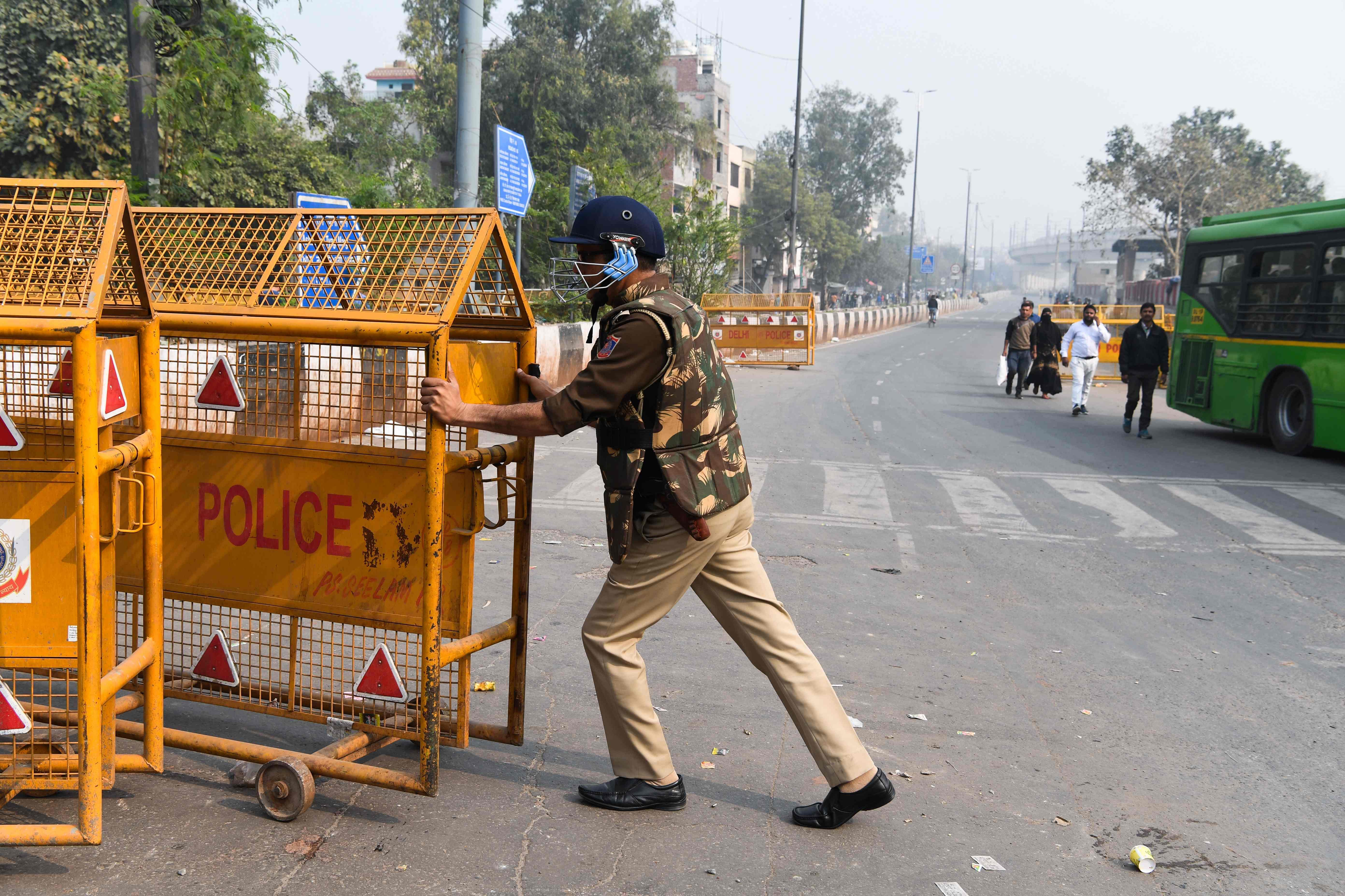 A security personnel adjusts road barriers on a street following clashes between people supporting and opposing a contentious amendment to India's citizenship law, in New Delhi. (AFP Photo)