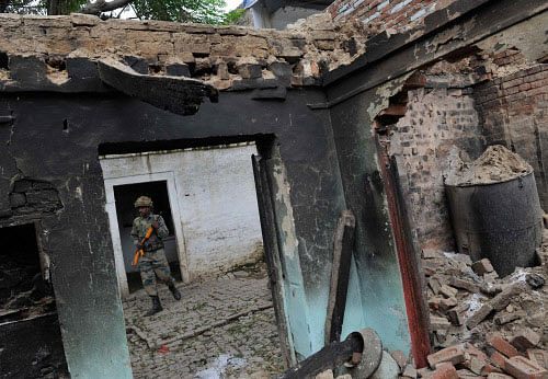 A security person walks in a burnt house at Kudba village in violence-hit Muzaffarnagar district on Wednesday. PTI Photo