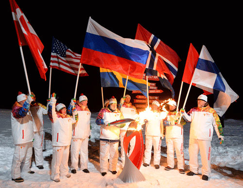 In this photo taken on Saturday, Oct. 19, 2013 and made available by olympictorch2014.com on Friday Oct 25, a group of torch bearers hold various countries national flags and an Olympic torch at the North Pole, Arctic Ocean. The average summer temperatures in the Canadian Arctic over the last century are the highest in the last 44,000 years, and perhaps as long ago as 120,000 years, a new study has found. AP file photo