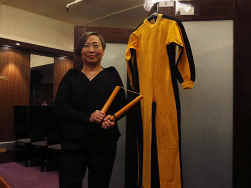 Auction house Spink vice chairman Lee poses with nunchaku and jumpsuit used by Bruce Lee during news conference in Hong Kong. Reuters Image