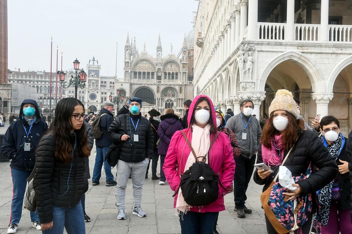 Tourists wearing protective masks visit Venice on February 25, 2020, during the usual period of the Carnival festivities which have been cancelled following an outbreak of the COVID-19 novel coronavirus in northern Italy
