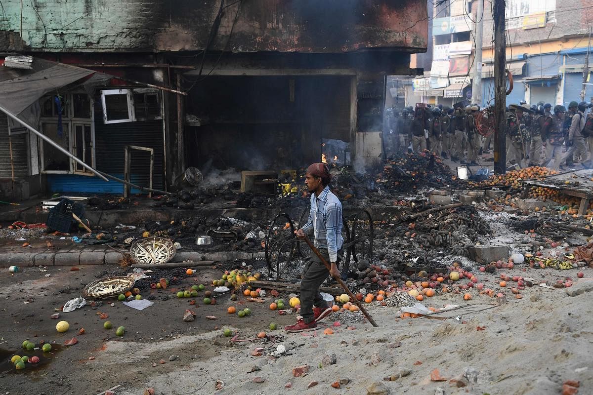 A man walks past a vandalised shop following clashes between supporters and opponents of a new citizenship law, at Bhajanpura area of New Delhi on February 24, 2020. Credit: AFP photo