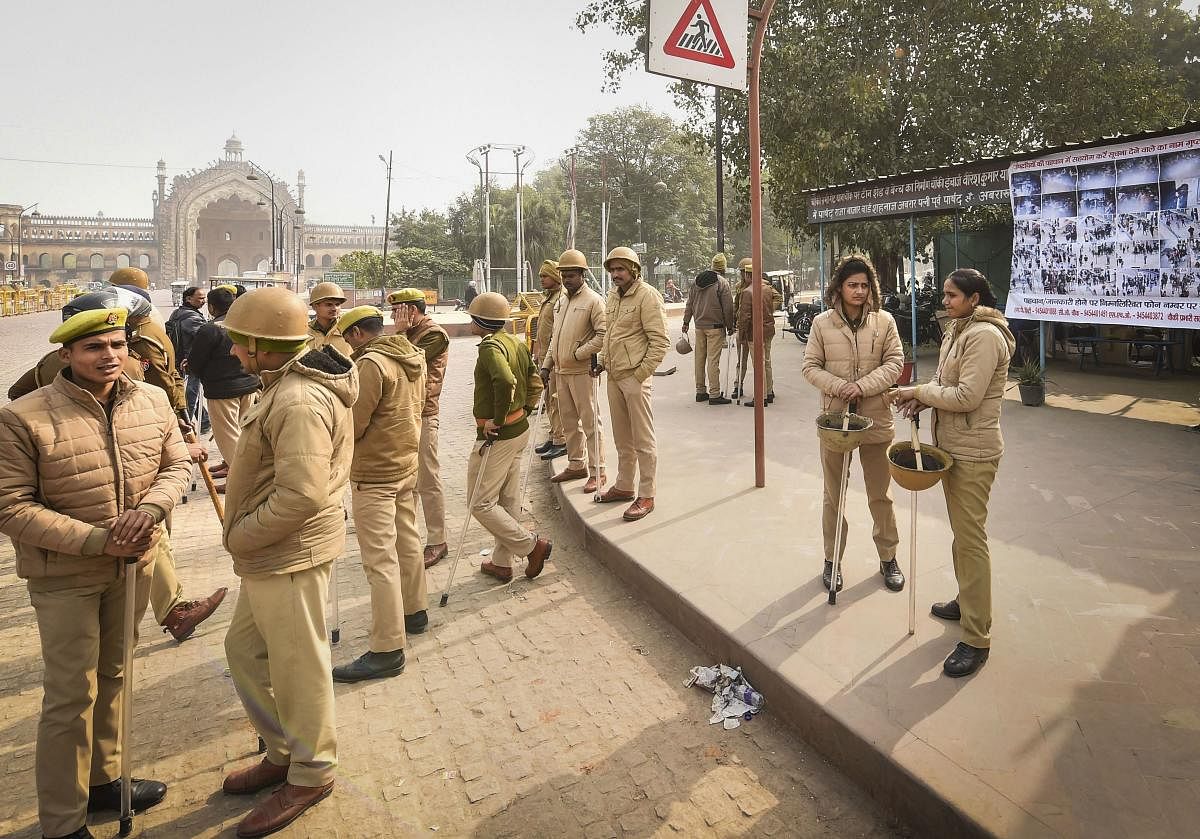  Police personnel stand guard beside a poster of protestors suspected to have incited vandalism during protests against CAA and NRC, in Lucknow, Friday, Dec. 27, 2019. (PTI Photo)
