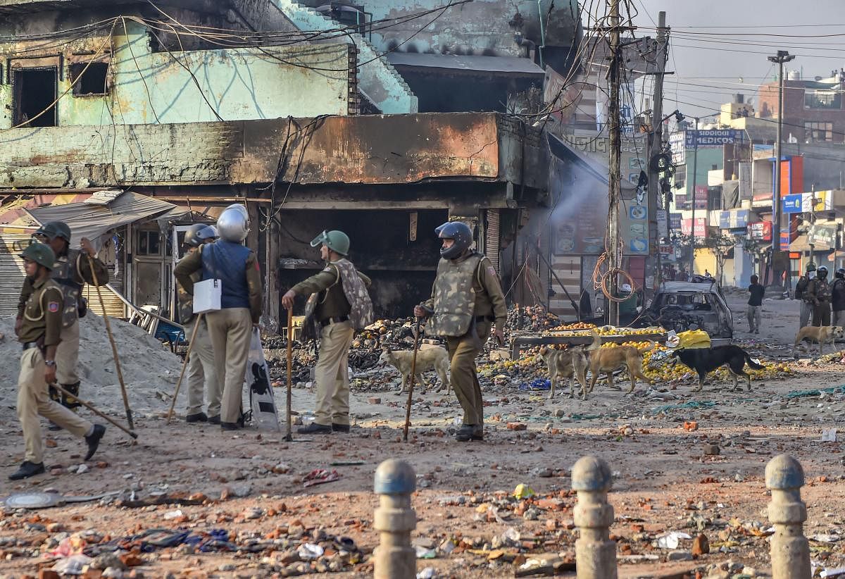  Security personnel stand guard near a neighbourhood vandalised by rioters during clashes between those against and those supporting the Citizenship (Amendment) Act in north east Delhi, Tuesday, Feb. 25, 2020. Credit: PTI Photo