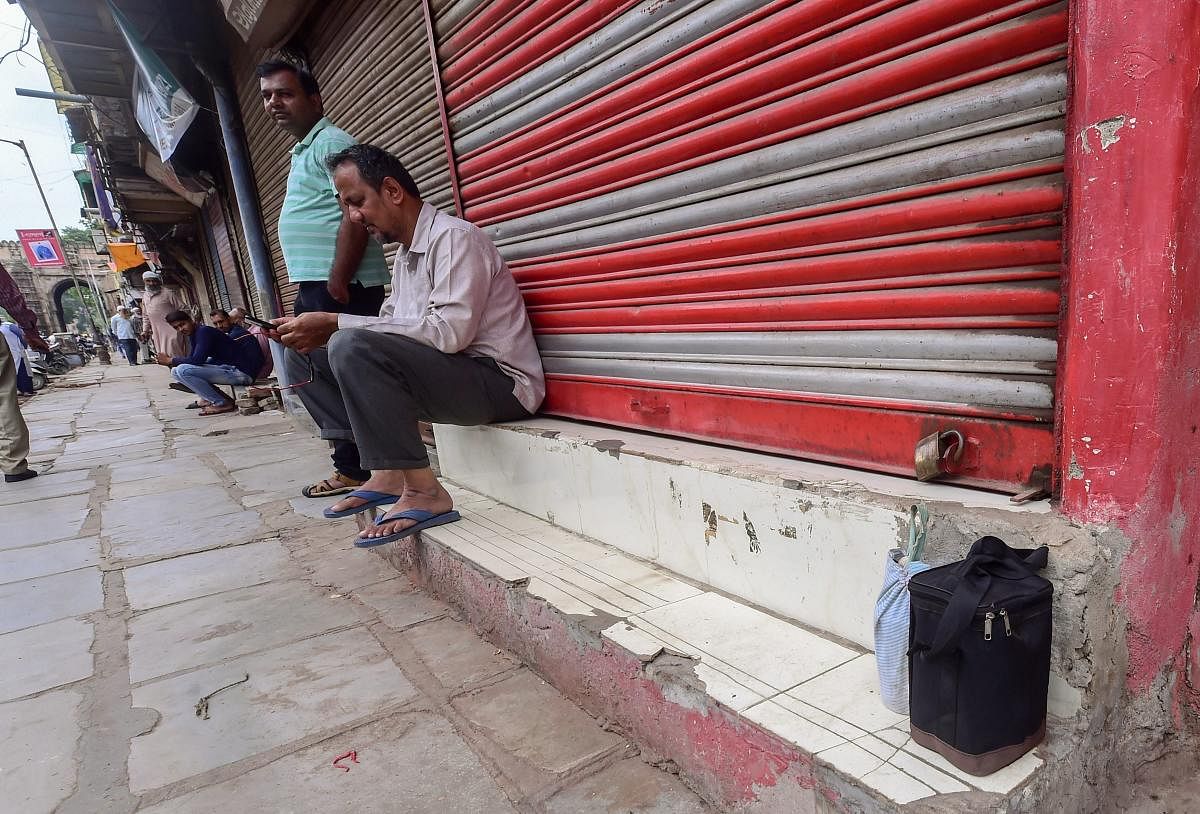 A man sits in front of a closed shop during 'Bharat Bandh' protest called by Congress and other parties against fuel price hike and depreciation of the rupee in Ahmedabad, on Monday. PTI