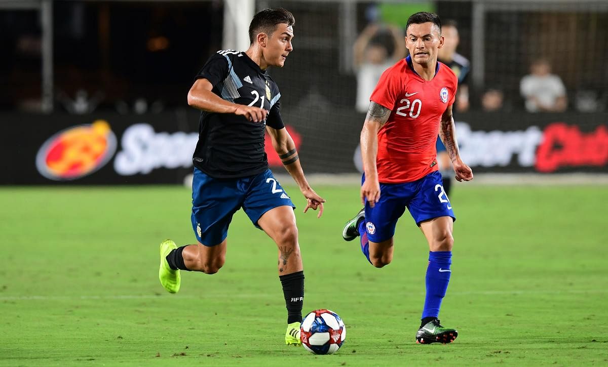 Paulo Dybala of Argentina runs with the ball under pressure from Charkes Arangiuz of Chile during their international soccer friendly at the Los Angeles Coliseum in Los Angeles on September 5, 2019. (Photo by Frederic J. BROWN / AFP)