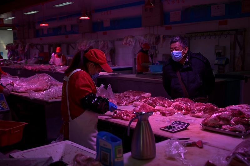 A customer wearing a face mask buys pork meat at a wholesale market for agricultural products, as the country is hit by an outbreak of the novel coronavirus, in Beijing, China. (Reuters Photo)