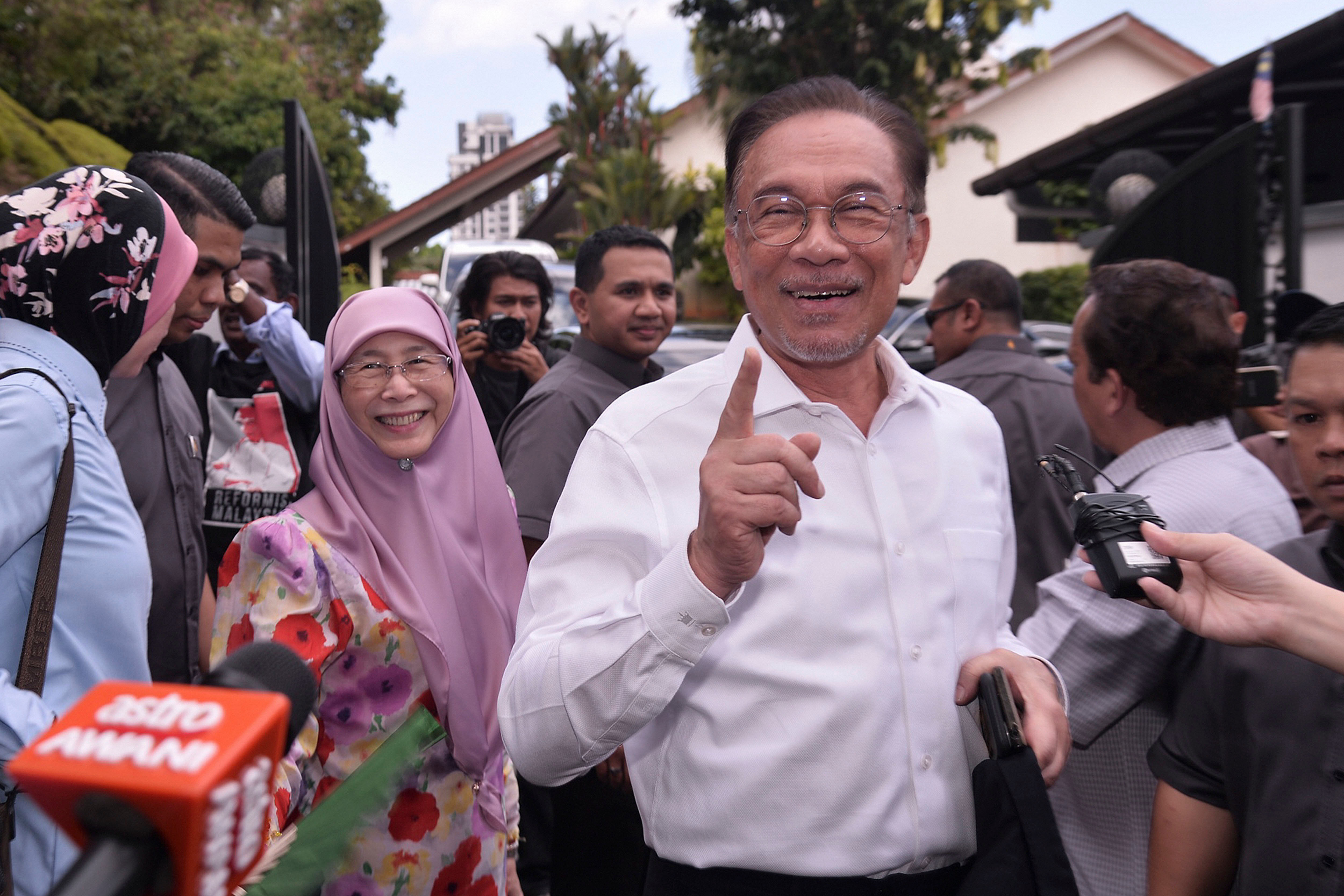 Politician Anwar Ibrahim, right, gestures next to his wife Wan Azizah Ismail as they head to their party headquarters after meeting the king in Kuala Lumpur.(Credit: AP Photo)