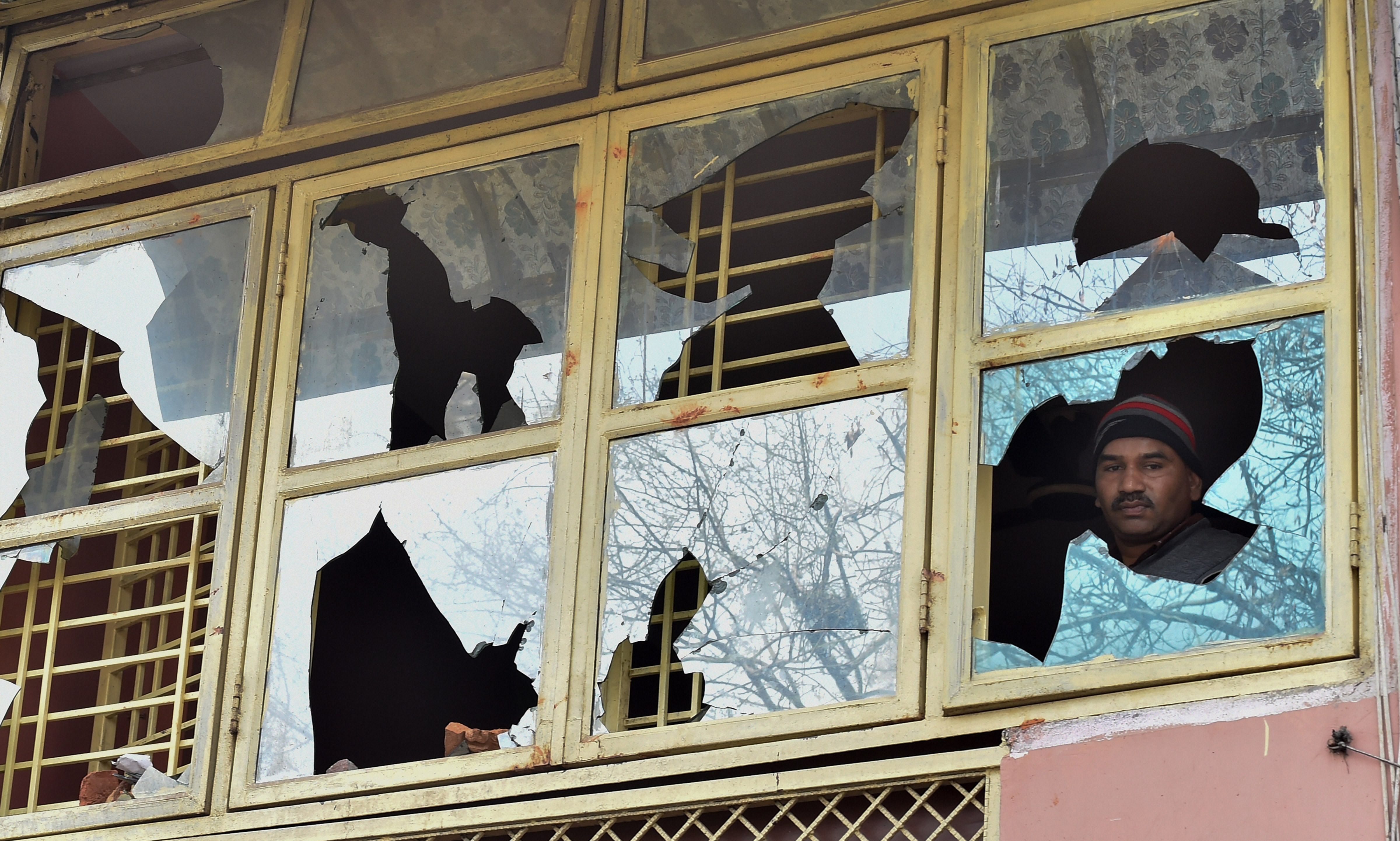 A resident looks though the damaged windows of his house, in Bhagirathi Vihar area of the riot-affected north east Delhi. (PTI Photo)