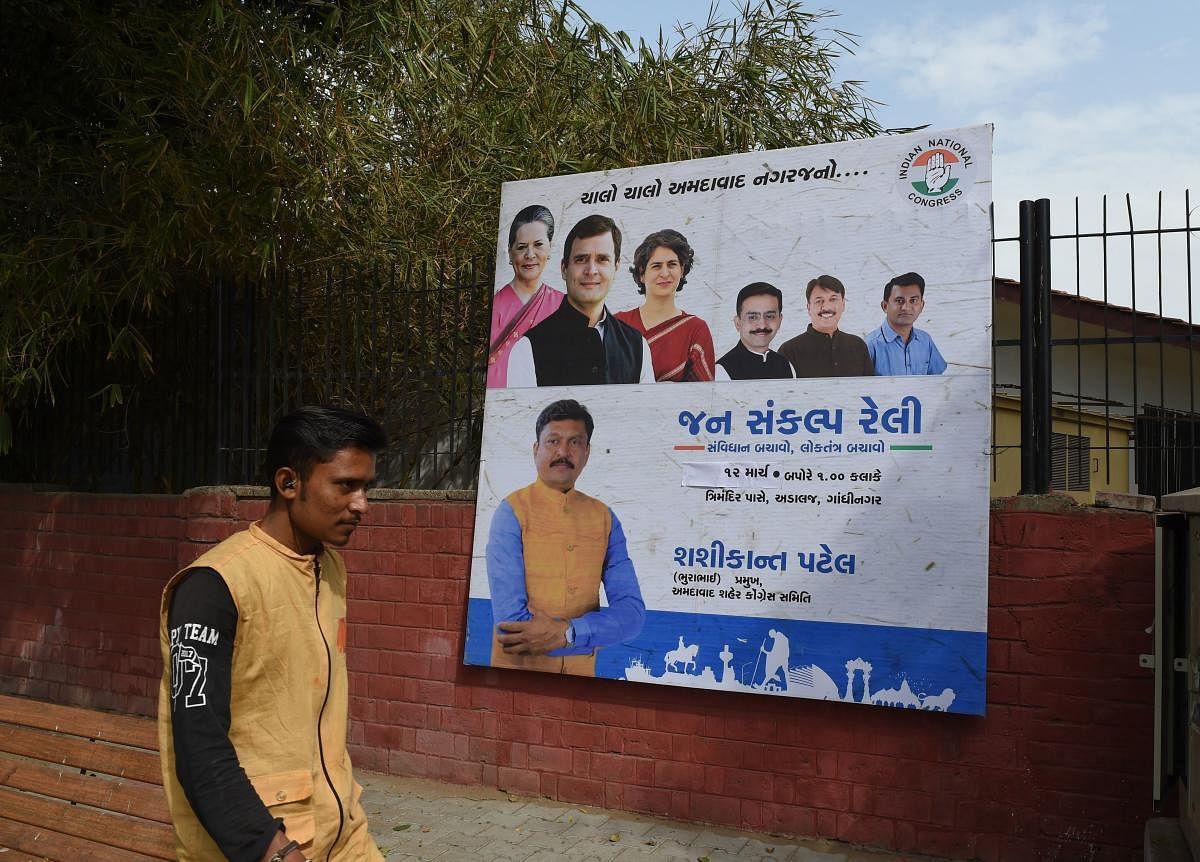 An Indian man walks in front of a billboard depicting India's Congress Party president Rahul Gandhi (2L), his mother United Progressive Alliance (UPA) chairperson Sonia Gandhi (L), sister Priyanka Gandhi Vadra (3L) along with senior Congress party leaders