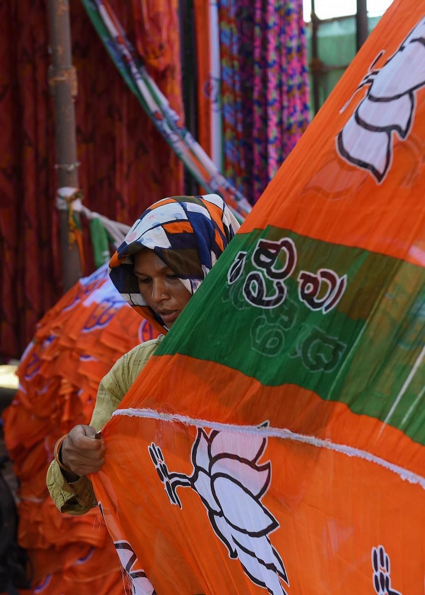 An Indian worker dries colourful materials dedicated to the Bhartiya Janta Party (BJP) campaigns ahead of India's general election, on the outskirts of Ahmedabad on March 11, 2019. - India's electoral commission announced national polls on March 10, with voting in the world's biggest democracy to run from April 11 to May 19. (Photo by SAM PANTHAKY / AFP)