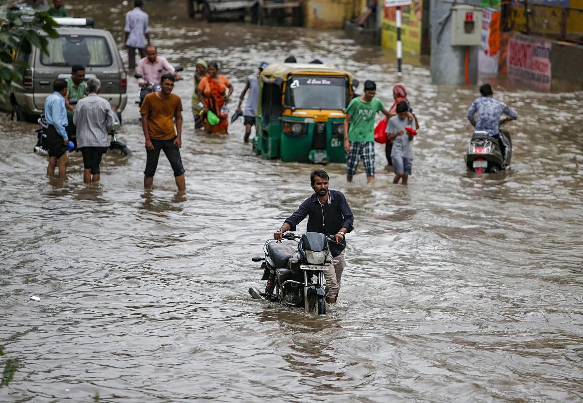 Commuters wade through a waterlogged street following heavy rains, in Ahmedabad, Tuesday, Sept 10, 2019. (PTI Photo)