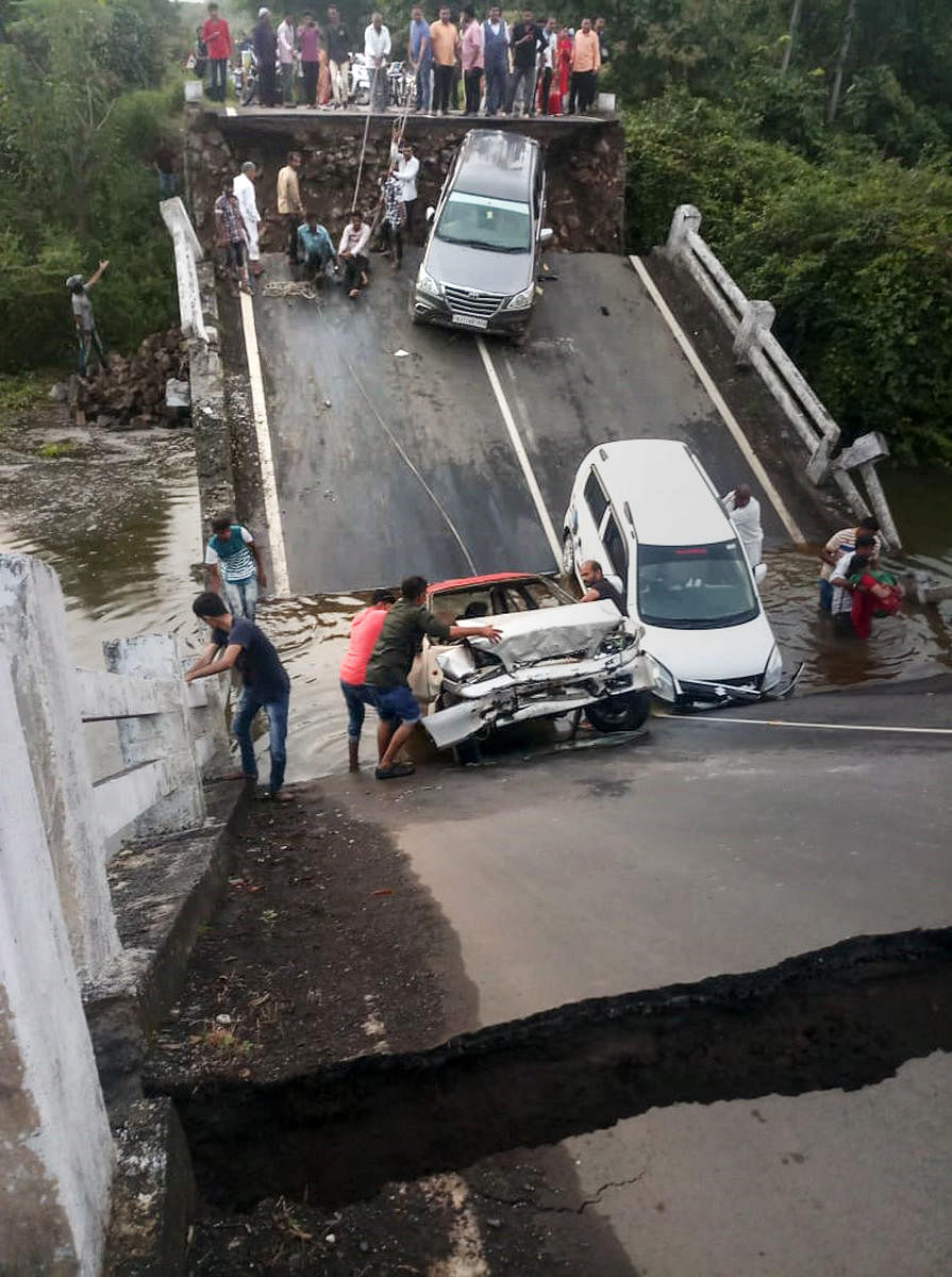 Vehicles stuck in the gaps after slabs of a 60-feet-long bridge collapsed in Junagadh district, Monday, Oct. 7, 2019. (PTI Photo)